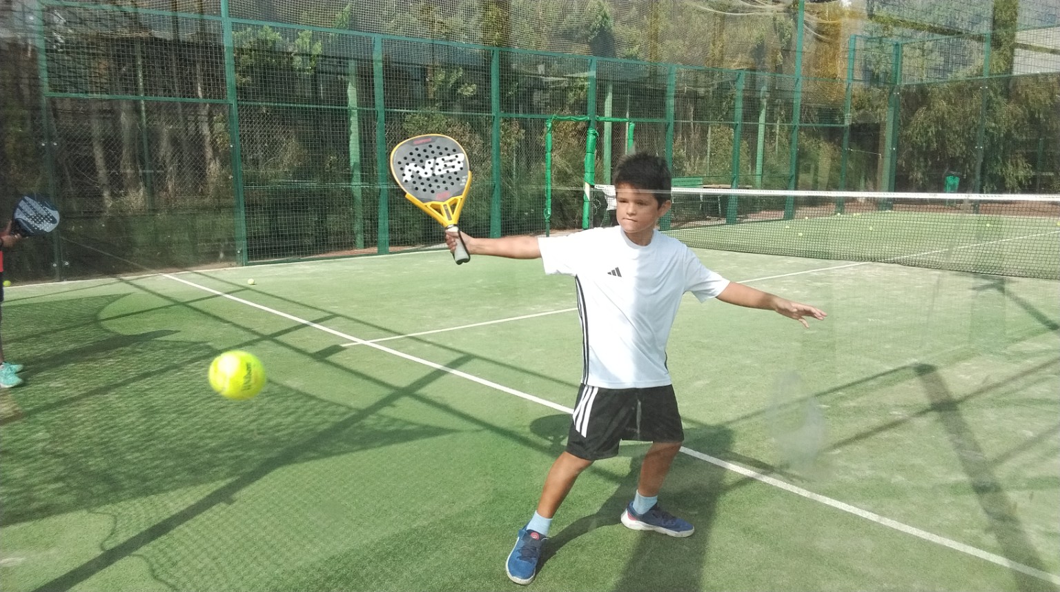 Jonge speler oefent een forehand op de padelbaan