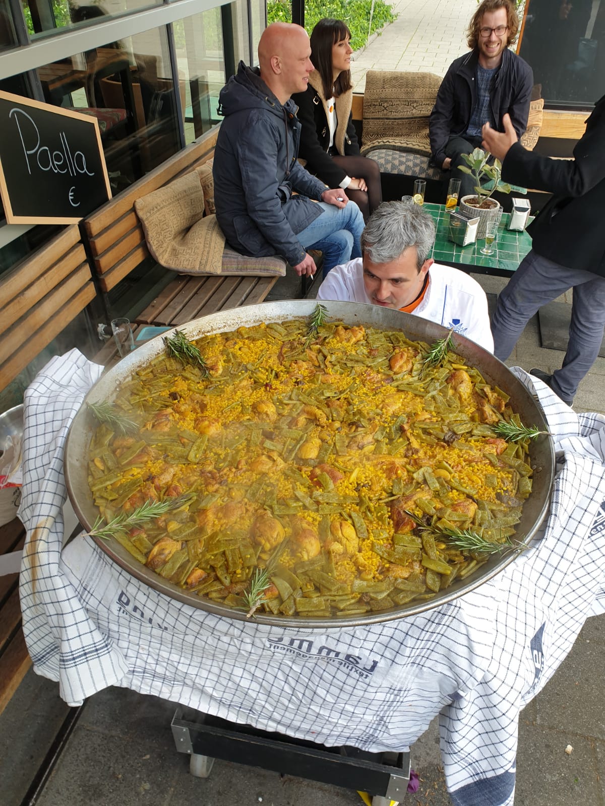 Gasten kijken toe terwijl Daniel de paella presenteert