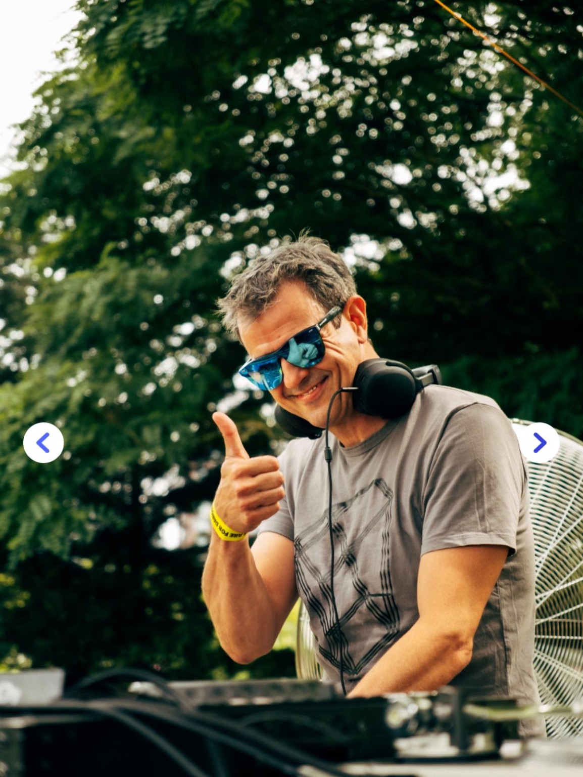 Daniel met blauwe zonnebril en een duim omhoog achter de DJ-booth